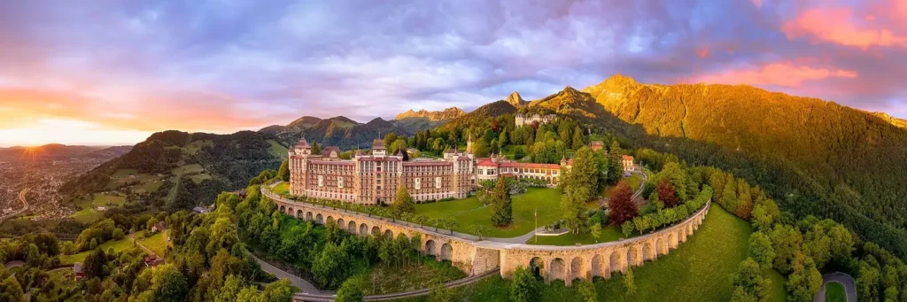 Hình ảnh toàn cảnh khuôn viên Caux Palace lộng lẫy rực rỡ dưới ánh hoàng hôn trên đỉnh núi tại Thụy Sĩ.