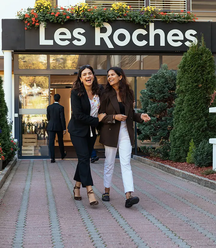 Cuộc sống sinh viên năng động tại trường quản trị khách sạn Les Roches Thụy Sĩ Hình ảnh hai nữ sinh viên quốc tế rạng rỡ bước ra từ sảnh chính của trường quản trị khách sạn Les Roches tại Thụy Sĩ.