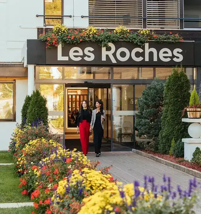 Sảnh chính trường quản trị khách sạn Les Roches Crans-Montana Thụy Sĩ Hình ảnh hai nữ sinh viên thanh lịch bước ra từ sảnh chính hiện đại của trường quản trị khách sạn Les Roches tại cơ sở Crans-Montana, Thụy Sĩ.